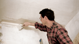 Picture of a guy fixing wall with wall filler