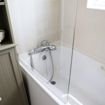 Image of a bathroom with bathtub shower screen and cabinet